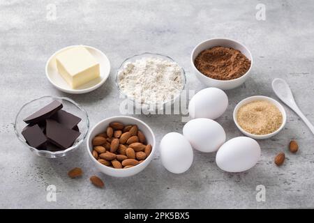 Ingredients for making chocolate cake: flour, chocolate, cocoa, eggs, almonds, brown sugar, butter on a gray textured background, top view. Cooking de Stock Photo