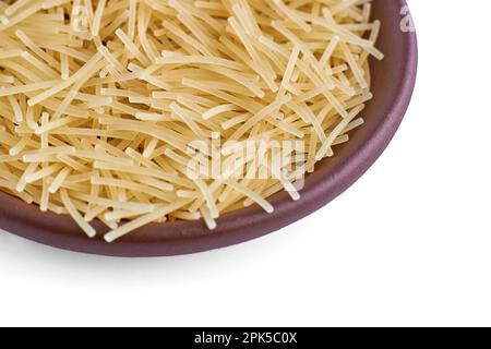 Pasta noodles in a clay ceramic bowl close-up isolated on a white background. Stock Photo