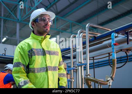 Engineer specialist using laptop checking and maintaining machine in factory Stock Photo