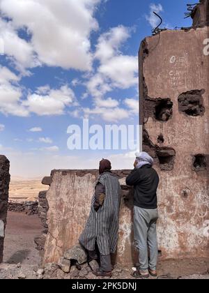 Merzouga, Morocco, Africa: moroccan people looking at panoramic road in the Sahara desert during ramadan near the fossil mines of Black Mountain are Stock Photo
