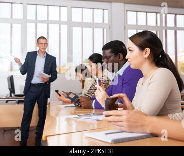 Adult student group using smartphones on lecture in classroom Stock Photo