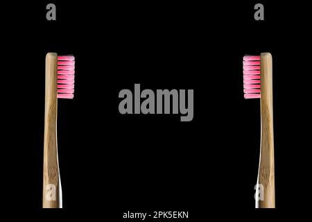 Eco friendly product concept. Zero waste two bamboo toothbrushes with pink bristle isolated on black background. Biodegradable material. Natural organ Stock Photo