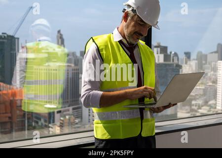 Close up view of male engineer with safety vest holding computer laptop working Stock Photo
