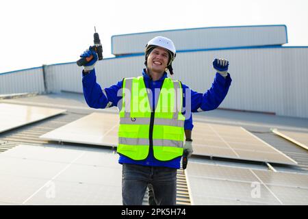 Happy engineers technicians installing solar panels on rooftop of plant Stock Photo