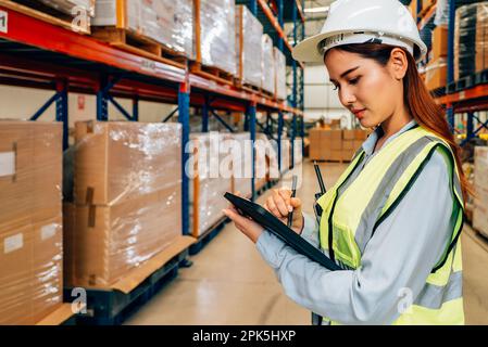 Warehouse manager in white helmet using tablet for checking goods on shelves Stock Photo