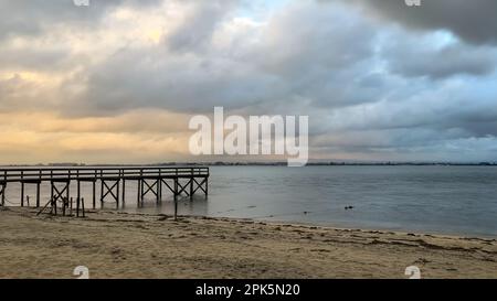 Empty wooden pier to the Ria de Aveiro in Portugal, with dramatic sky and calm water. Torreira, Murtosa - Portugal. Stock Photo