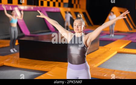 Adult woman trains jumping in trampoline center Stock Photo