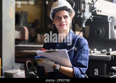 Portrait of happy female industrial worker in white hard hat smiling Stock Photo