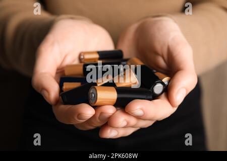 Woman holding many used electric batteries in her hands, closeup Stock Photo
