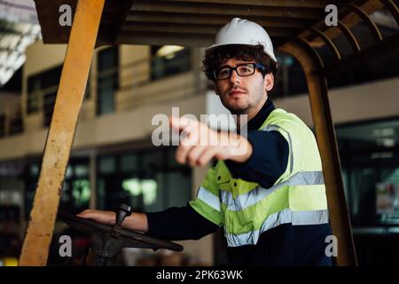 Male industrial engineer in white hard hat driving forklift  Stock Photo