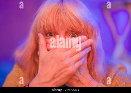 woman with hands over mouth expressing surprise Stock Photo