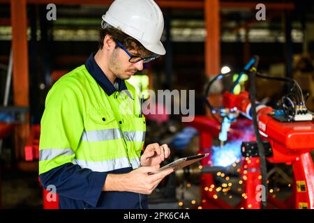 Young mechanical technician using tablet checking machine at warehouse Stock Photo