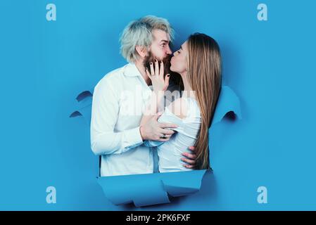 Couple in hole paper. Discount and sale. Kissed couple of bearded man and happy woman making hole in paper kiss through hole. Advertising board, blue Stock Photo