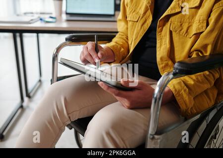 Closeup image of young man in wheelchair drawing sketch on digital tablet Stock Photo