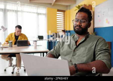 Frowning businessman in wheelchair working on laptop in office Stock Photo