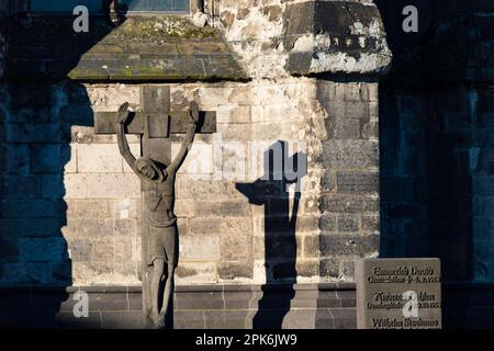 Stone cross with shadow cast, cathedral cemetery near Cologne Cathedral, Cologne, North Rhine-Westphalia, Germany Stock Photo