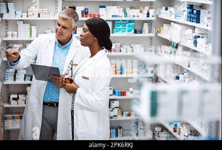 This one sells fast. two pharmacists working together in a drugstore. Stock Photo