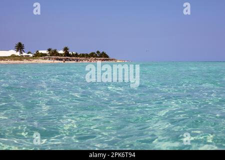 View from water surface to tropical beach and coconut palm trees. Sea resort on Caribbean island with transparent water Stock Photo