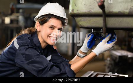 Happy female technician engineer worker checking and inspecting machine Stock Photo