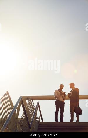 Networking is important in business. Low angle shot of two businessmen talking on top of stairs outside. Stock Photo