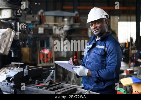 Professional male industrial worker in white hard hat working at manufacturing Stock Photo