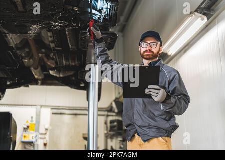 Caucasian professional mechanic making chassis inspection in the car workshop, medium shot. High quality photo Stock Photo