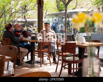 Yerevan, Armenia - 27 March 2023: Senior friends in a cozy outdoor cafe are drinking coffee, smoking and talking about life, selective focus Stock Photo