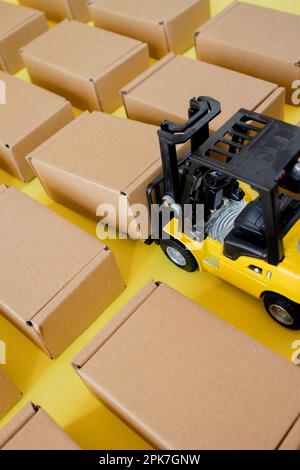 Forklift truck raises cardboard boxes on a yellow background. Cargo ...