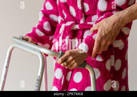 unrecognizable woman being assisted to walk using a walker by caregiver Stock Photo
