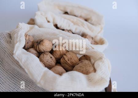 Shelled walnuts, pile of walnuts with shelled in three white cloth bags on a white background one after another. Cloth bags full of shelled walnuts. Stock Photo
