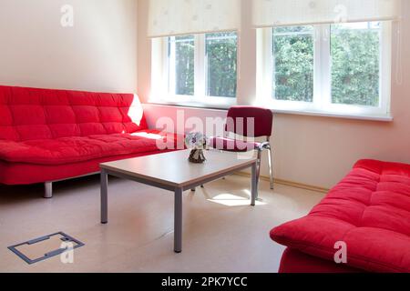 A staff room in a school, two red sofas and a table. Stock Photo