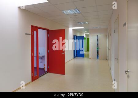 A school corridor with coloured doors opening off it.  Red,blue and green doors. Lockers and cupboards. Stock Photo