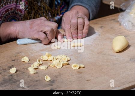Wrinkled hands of an elderly woman preparing fresh orecchiette or orecchietta, made with durum wheat and water, handmade pasta typical of Puglia Stock Photo