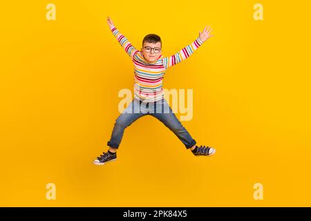 Full length photo of active kid boy jumping up raising hands isolated on vibrant color background Stock Photo