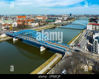 Bridges on Vistula River in Krakow, Poland. Aerial view. Boulevards with waking people. Blue tied-arc bridge in front. Footbridge for pedestrians and Stock Photo