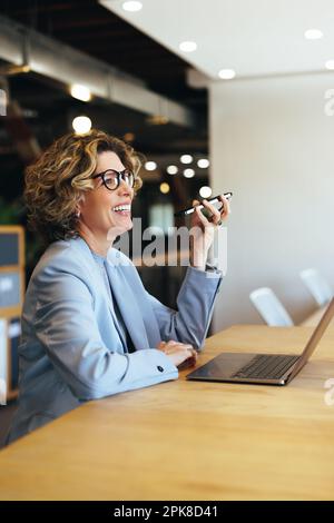 Happy business woman having a phone call conversation in an office. Professional woman speaking with her associates on a mobile phone. Woman sitting w Stock Photo