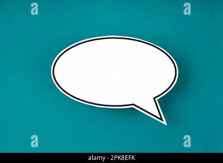 White speech bubble shaped post it note on green background with copy space. Stock Photo