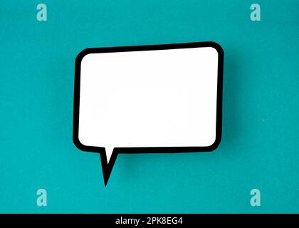 White speech bubble shaped post it note on green background with copy space. Stock Photo
