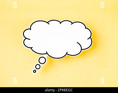 White speech bubble shaped post it note on yellow background with copy space. Stock Photo