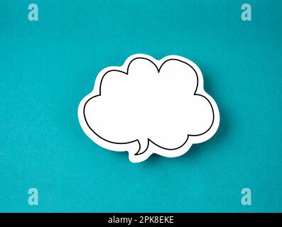 White speech bubble shaped post it note on green background with copy space. Stock Photo
