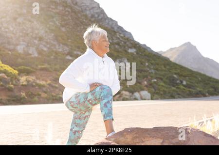 Happy senior plus size woman with earphones sitting on yoga mat outdoors  resting after exercises Stock Photo by Kiwitanya