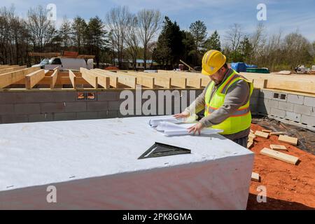 Having been an experienced build engineer in both safety and holding blueprint project doing monitoring on construction site of building project Stock Photo