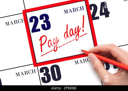 23rd day of March. Hand writing text PAY DATE on calendar date March 23 and underline it. Payment due date. Reminder concept of payment. Spring month, Stock Photo