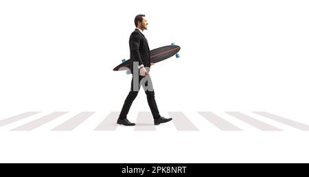 Full length profile shot of a businessman in a suit walking at a pedestrian crossing and holding a longboard isolated on white background Stock Photo