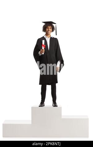Male african american student in a graduation gown holding a diploma and standing on a winner pedestal isolated on white background Stock Photo
