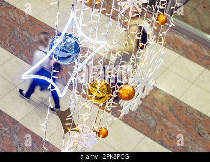 People walk under the Christmas decorations hanging in the airport hall Stock Photo