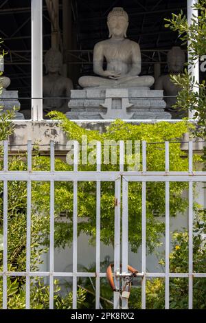 A locked gate in front of a building with seated Buddha statues, Thailand Stock Photo