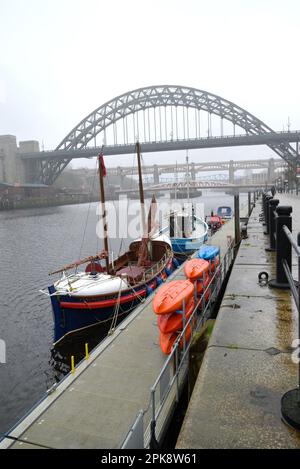Newcastle upon Tyne, Tyne and Wear, England, UK. Tyne Bridge (1928) over the river, on a grey, rainy day. Tynemouth Lifeboat moored by the quayside Stock Photo