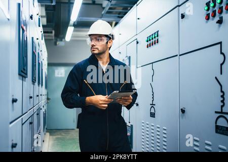 Electrician worker using tablet controlling machine at factory Stock Photo