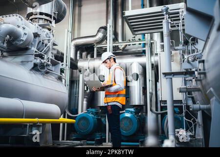 Engineer specialist using laptop controlling machine at factory Stock Photo